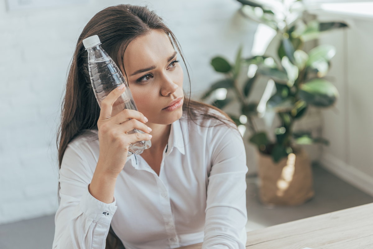 frau im büro mit wasserflasche