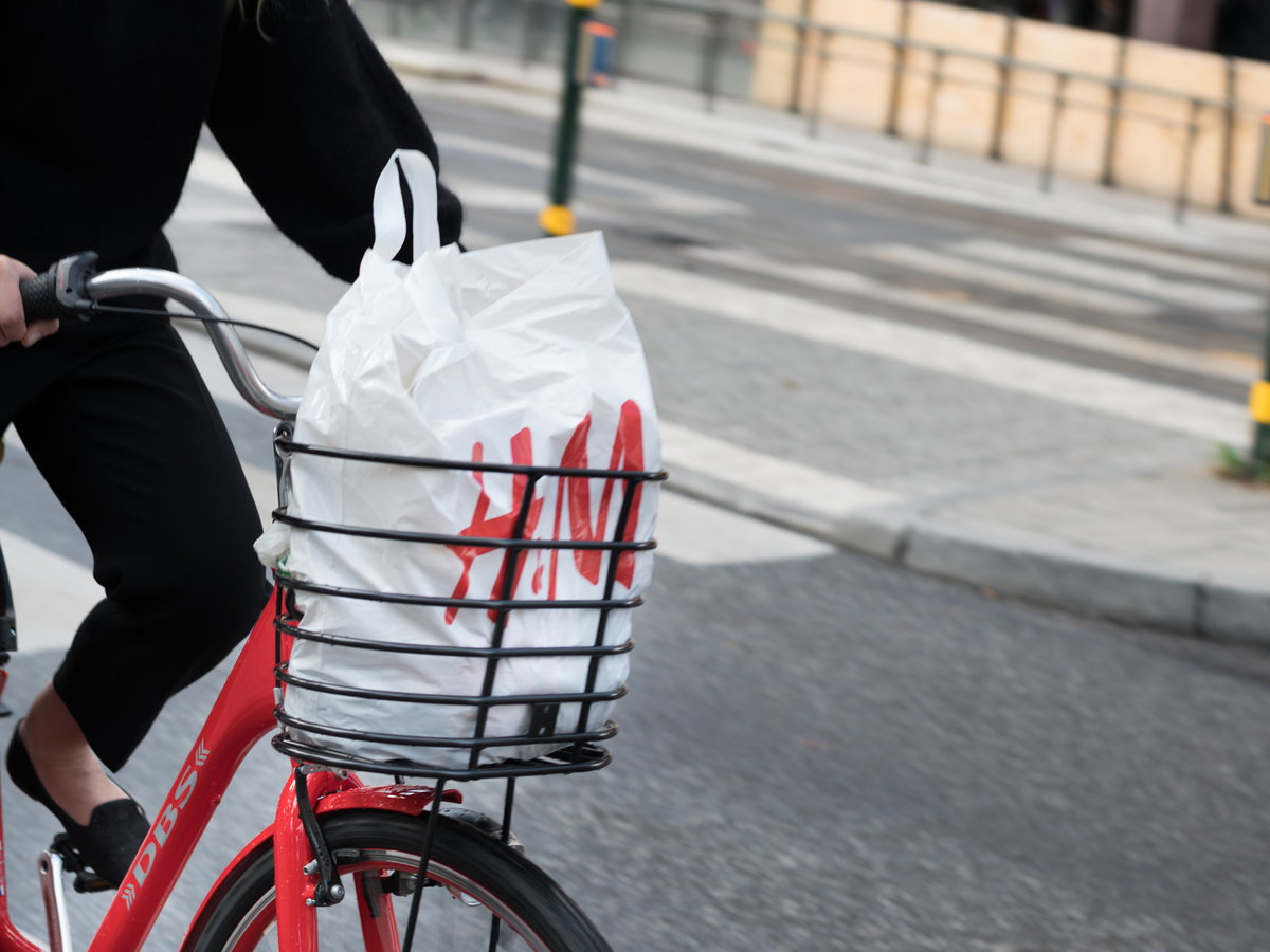 Rotes Fahrrad mit H&M-Tüte im Fahrradkorb auf Straße