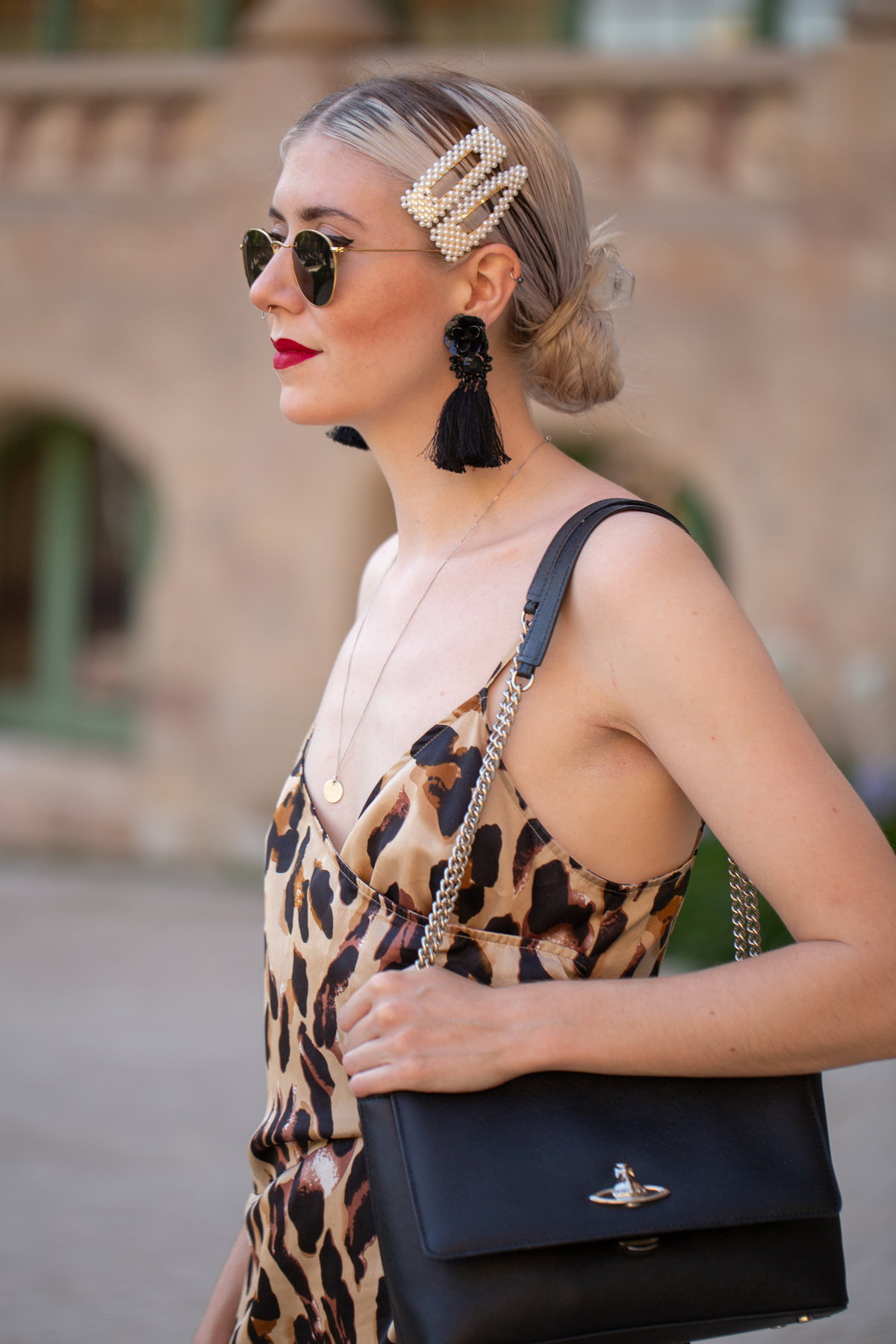 Blonde Frau mir Leo-Kleid, schwarzer Tasche und Haarspangen im Haar
