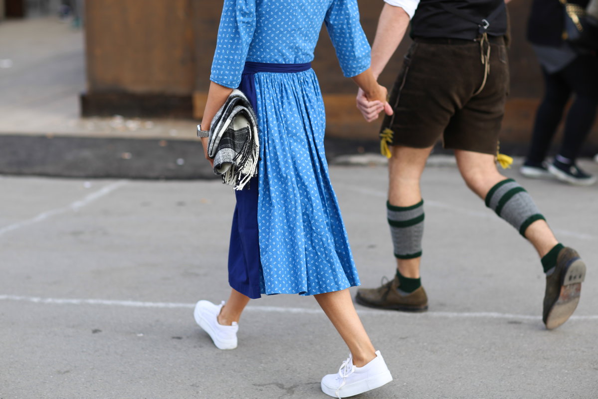 Eine Frau trägt ein Dirndl und weiße Sneaker