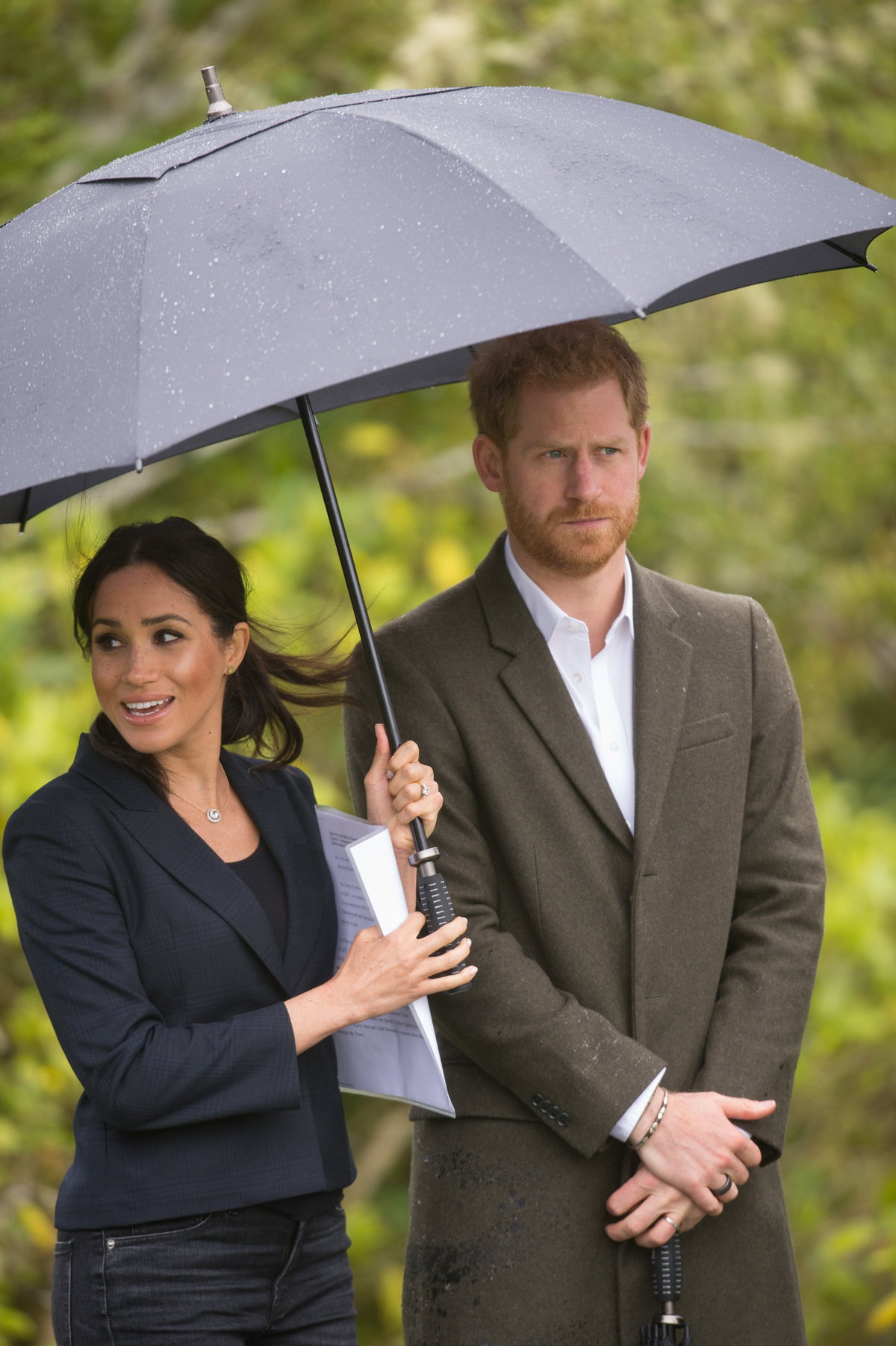 Meghan Markle hält den Regenschirm für Prinz Harry