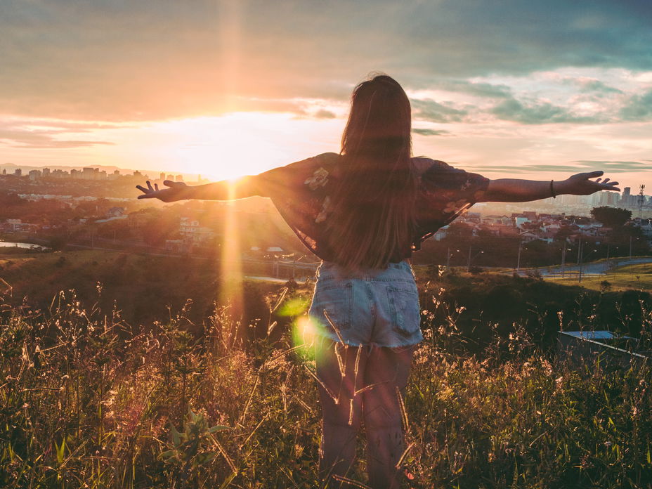 Horoskop Thema: Frau steht auf Berg bei Sonnenuntergang