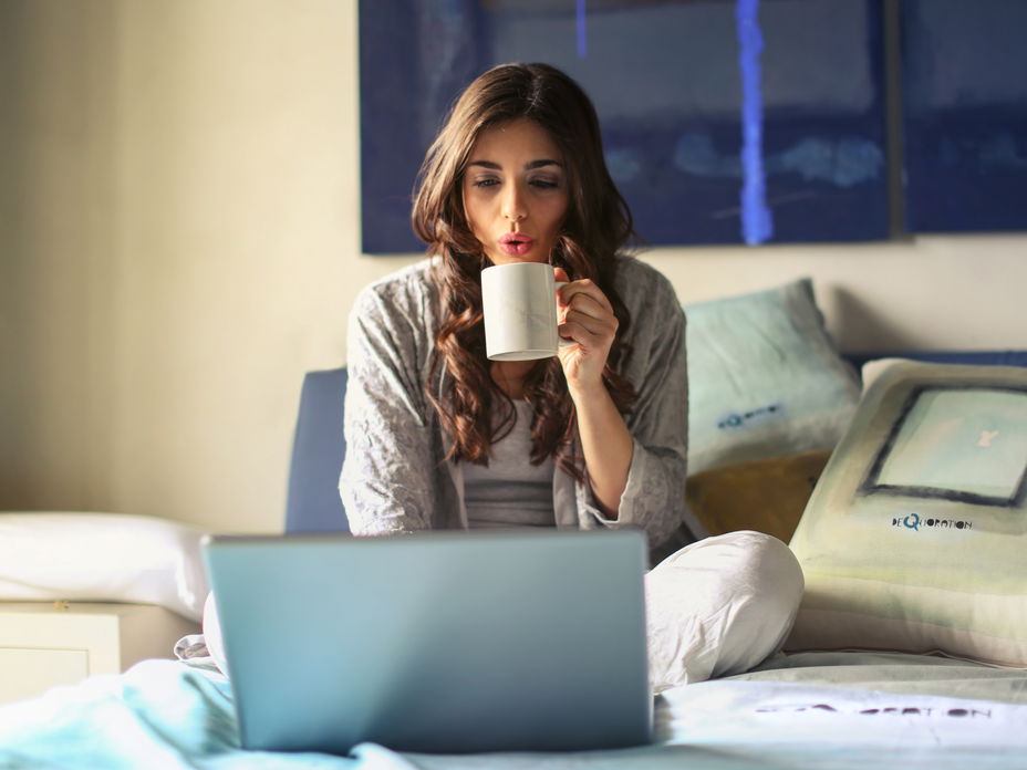 frau im bett mit kaffee und laptop