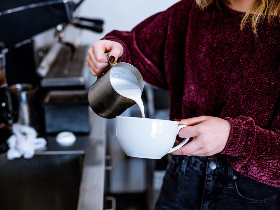 Frau gießt Milch in Tasse