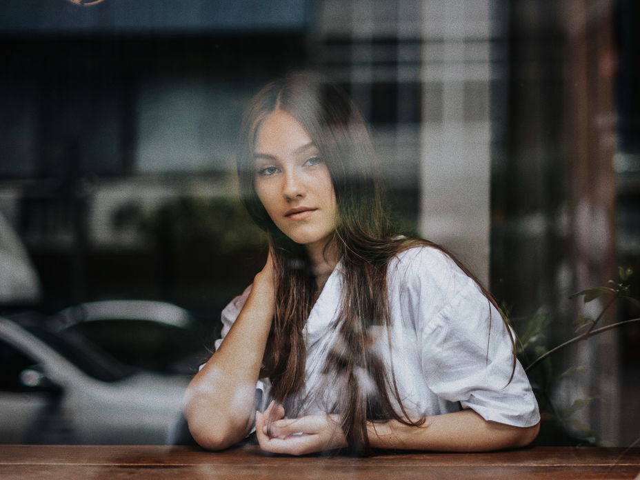 Frau sitzt hinter Fensterscheibe