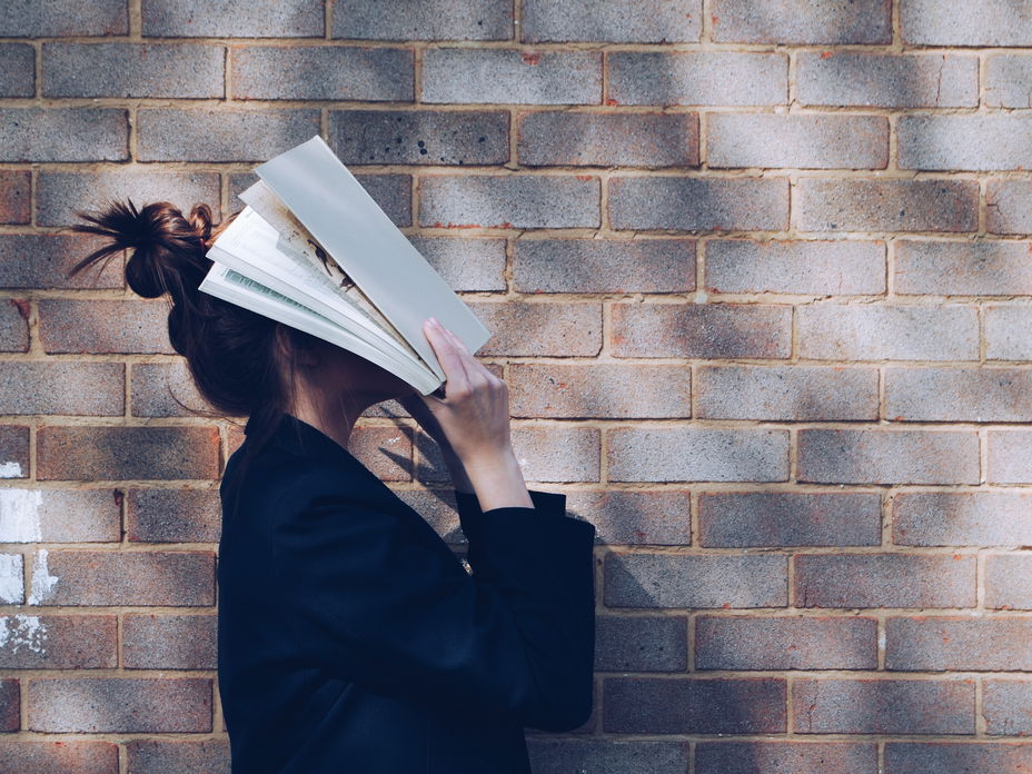 Frau schlägt sich ein Buch über den Kopf