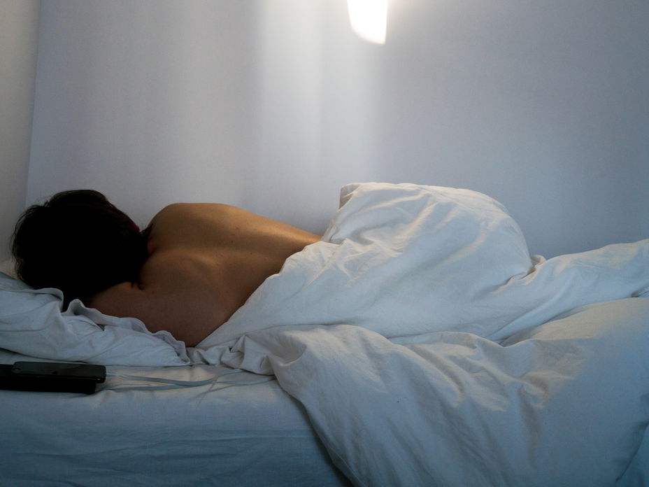 Rücken einer Frau die im Bett liegt