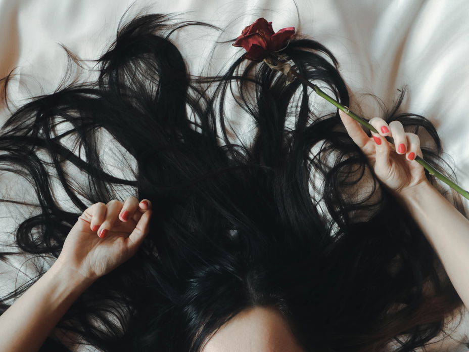 Frau mit schwarzen Haaren liegt auf dem Bett