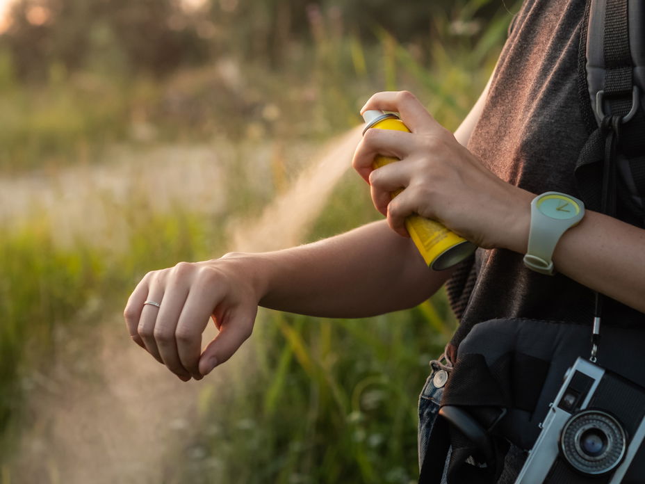 Frau sprüht Spray gegen Mückenstiche