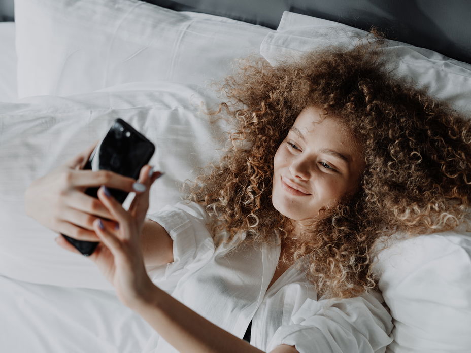 Frau im Bett mit einem Handy