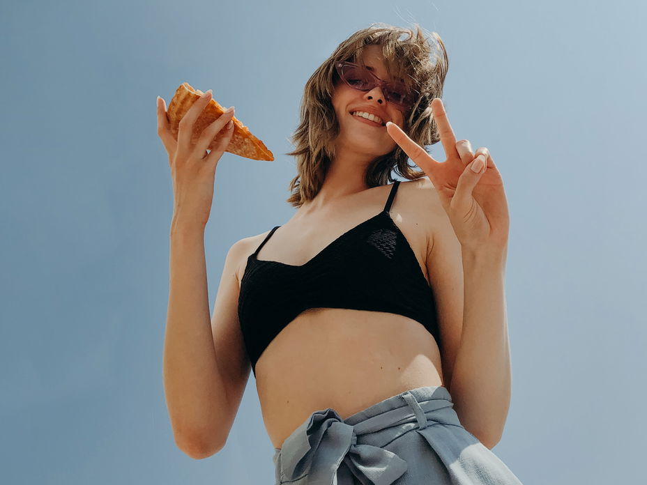 Frau mit einem Pizza Stück in der Hand