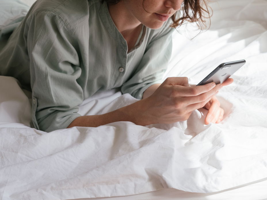 Frau auf einem Bett mit Handy