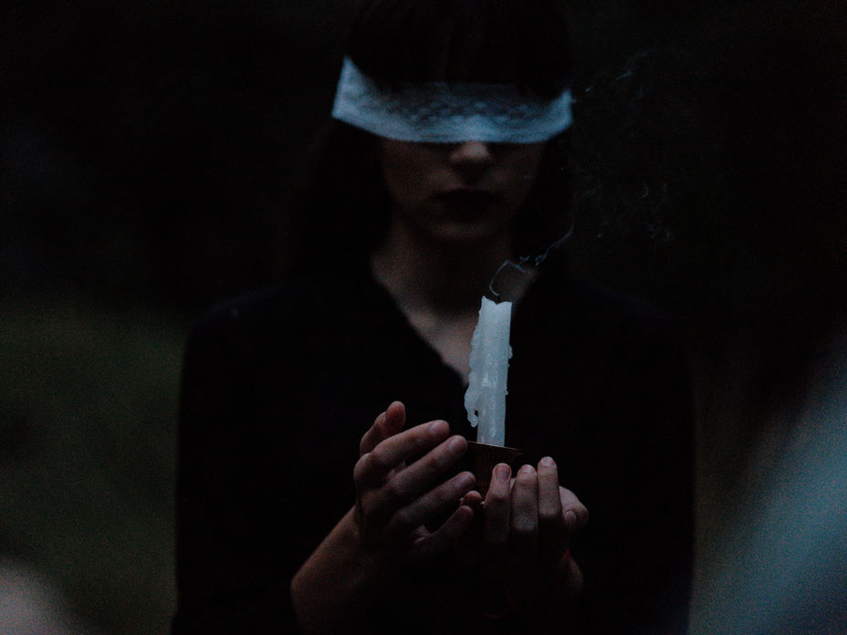 Mädchen mit verbundenen Augen und Kerze in der Hand