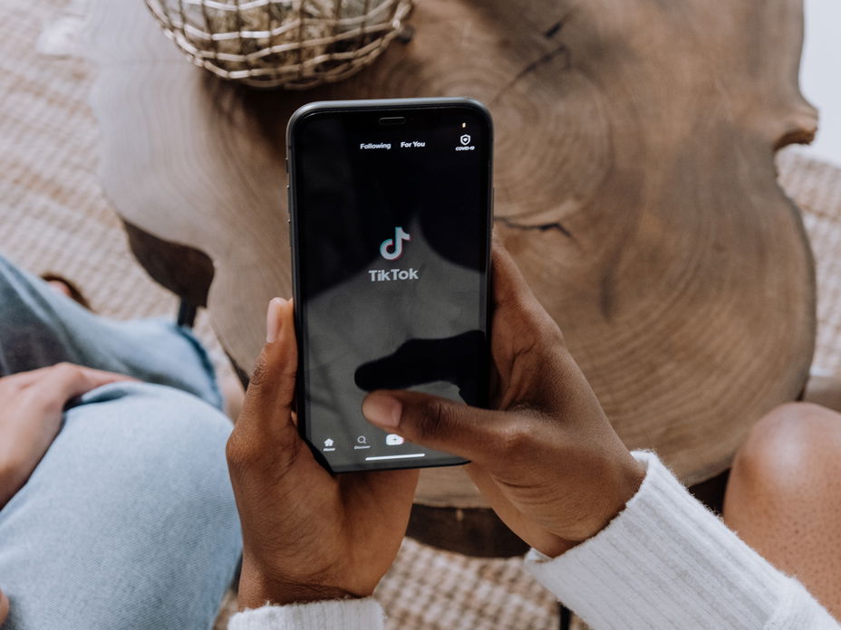 Frau hält Handy mit TikTok App hoch