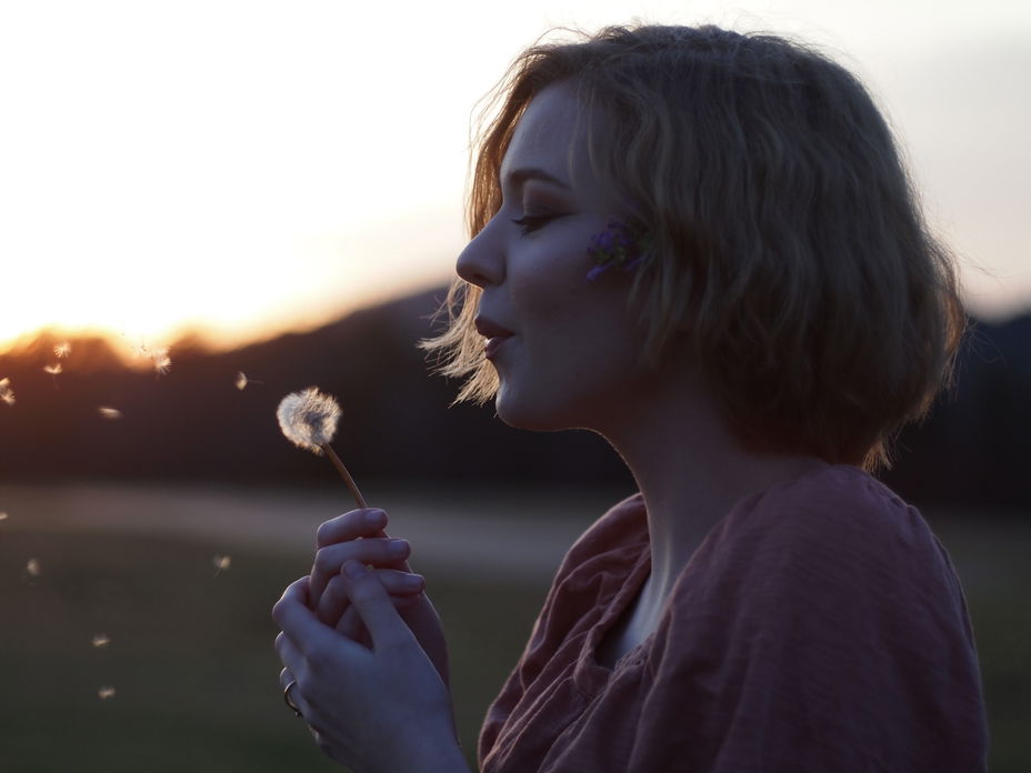 Frau pustet Pusteblume