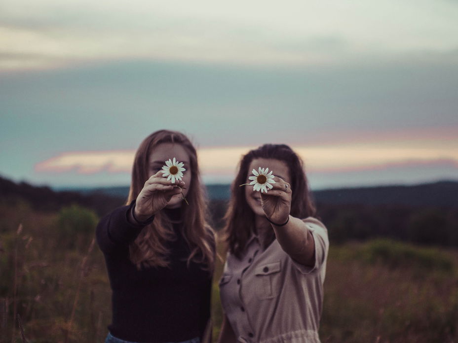 Zwei Frauen halten Blume in die Kamera