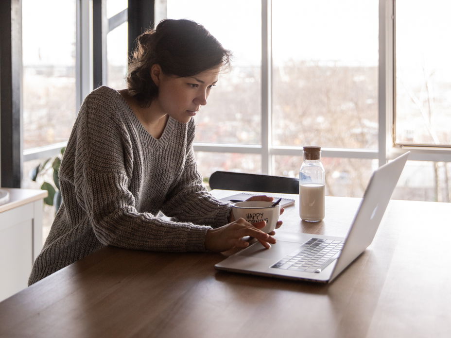 Frau beim Essen am Laptop im Homeoffice