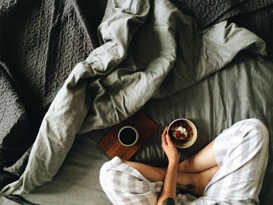 Frau sitzt mit Frühstück im Bett