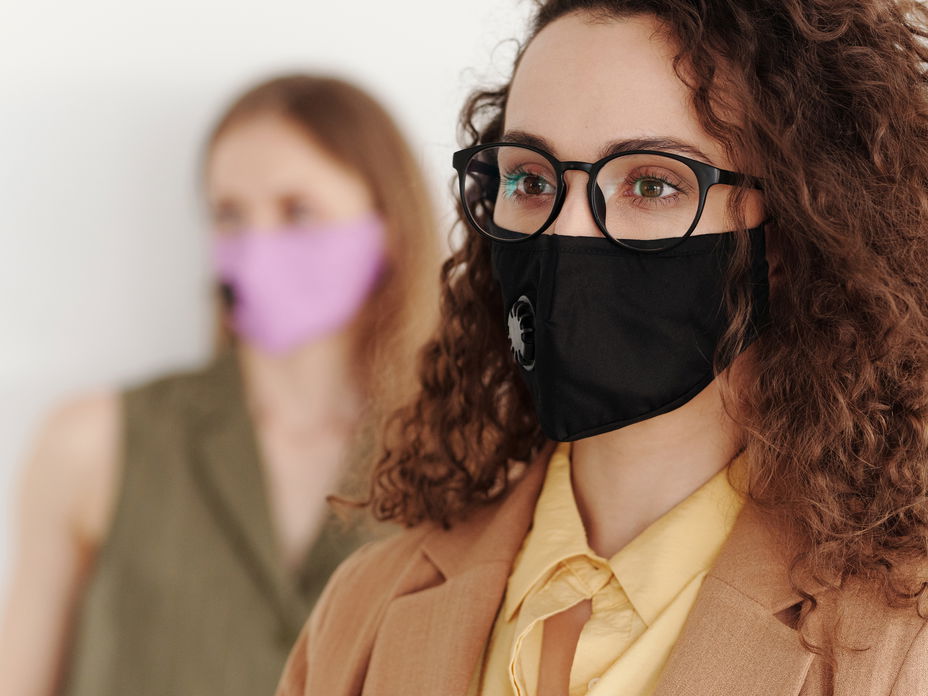 Frau mit schwarzer Brille und Mundschutz