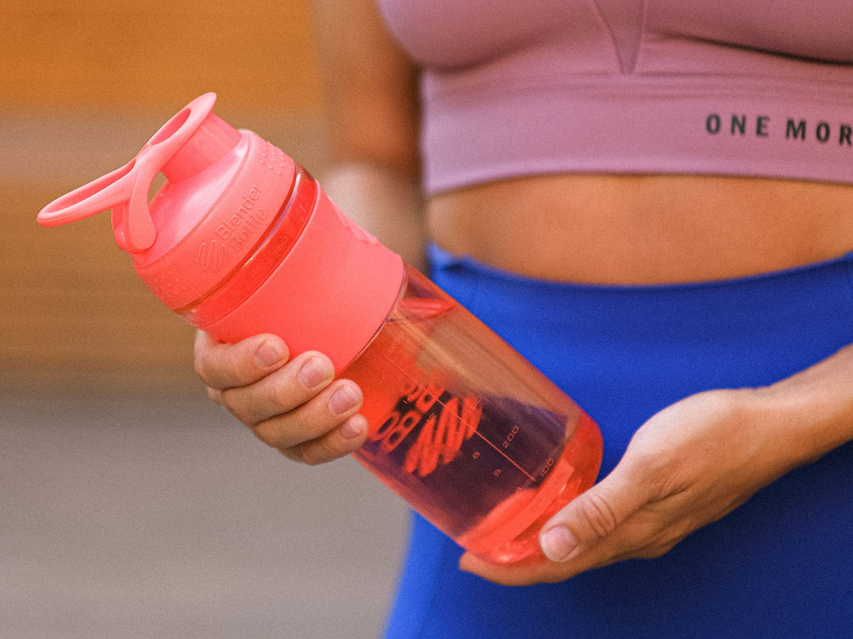 Frau im Sport-Outfit hält Flasche