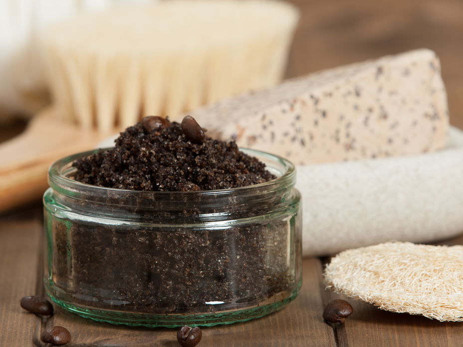 Kaffeepeeling im Glas, dahinter Seife und eine Trockenbürste