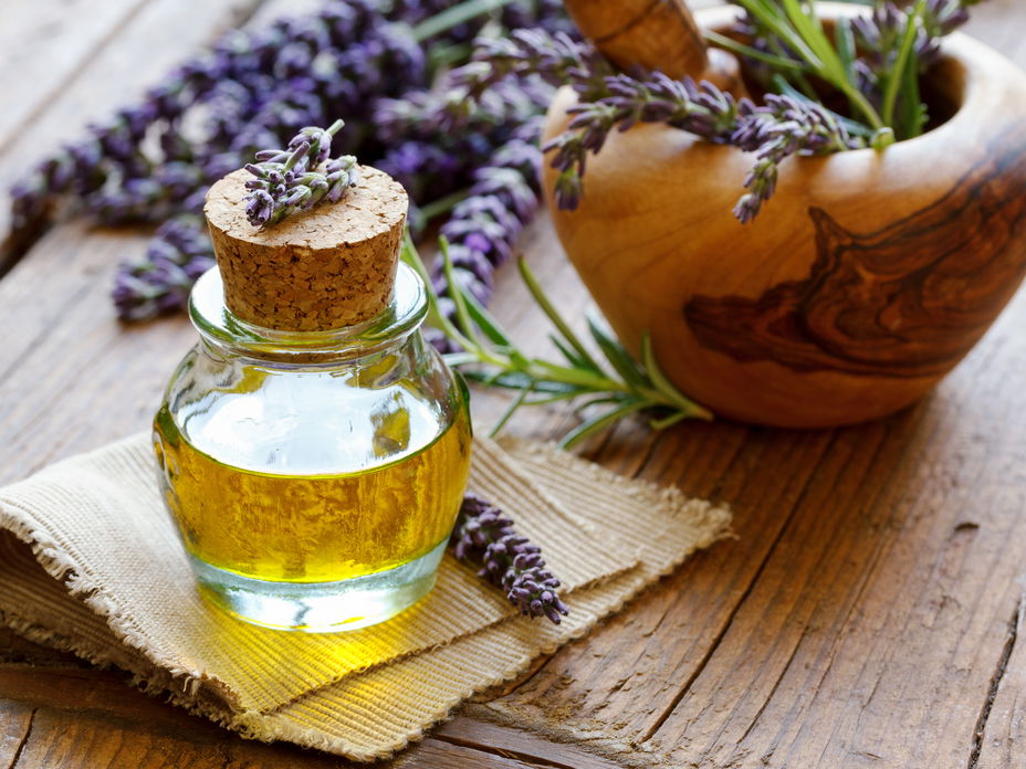 Lavendelöl in einer Flasche auf einem Holztisch mit Lavendelblüten