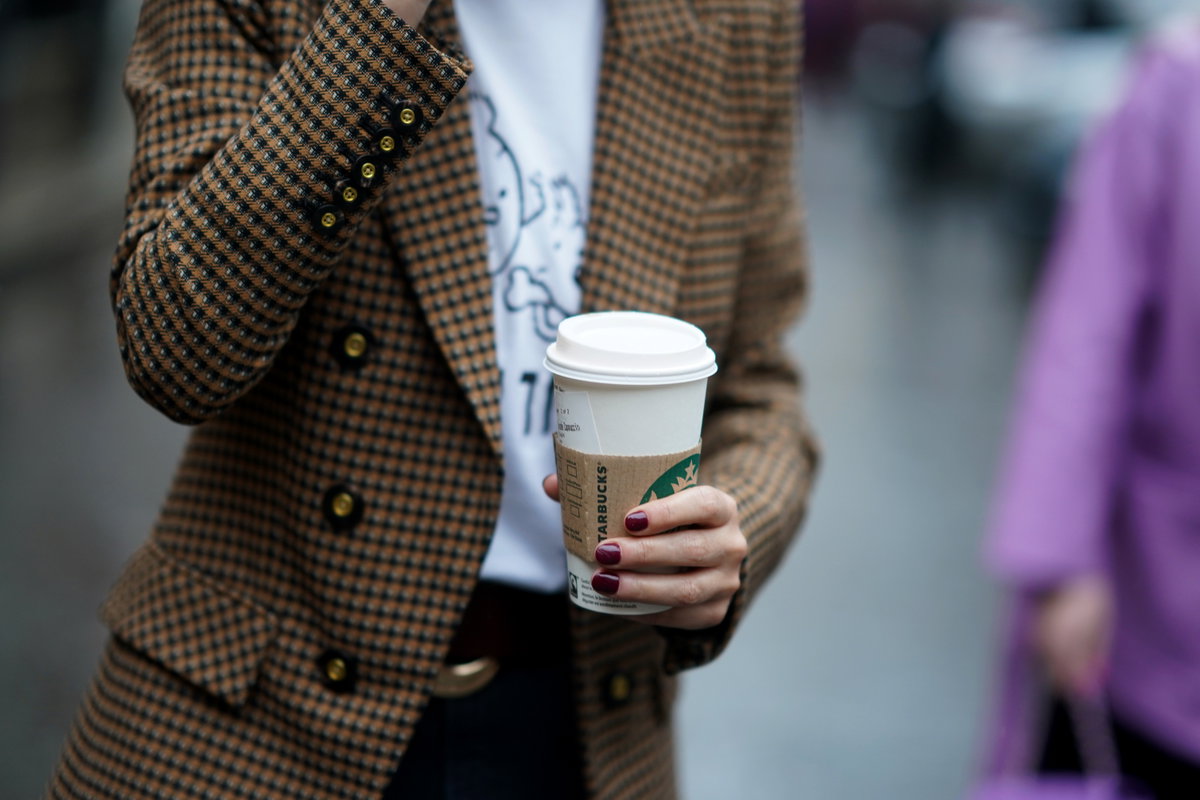 Frau mit lackierten Nägeln und Starbucks Kaffee To Go Becher