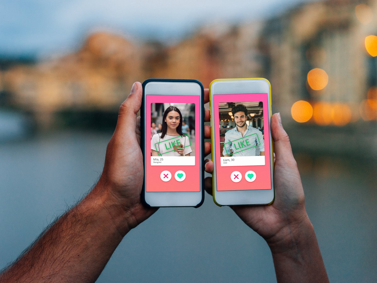Hand von Mann und Frau mit Smartphone jeweils in der Hand, auf welchem Tinder geöffnet ist