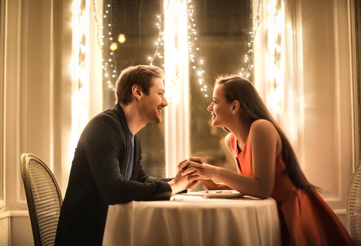 Valentinstag Date: Mann und Frau sitzen an einem Tisch der mit Lichterketten geschmückt ist