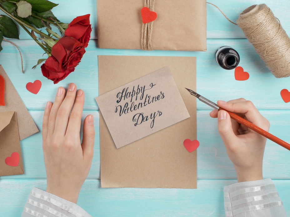 Valentinstag Sprüche: Zwei Hände schreiben eine Valentinstag Karte