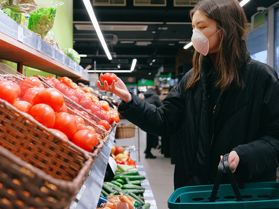 Frau haelt Tomate im Supermarkt