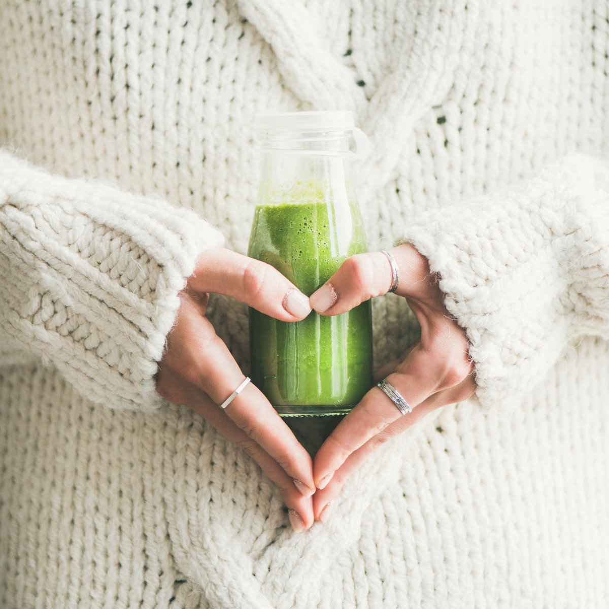 Frau hält einen grünen Smoothie in der Hand