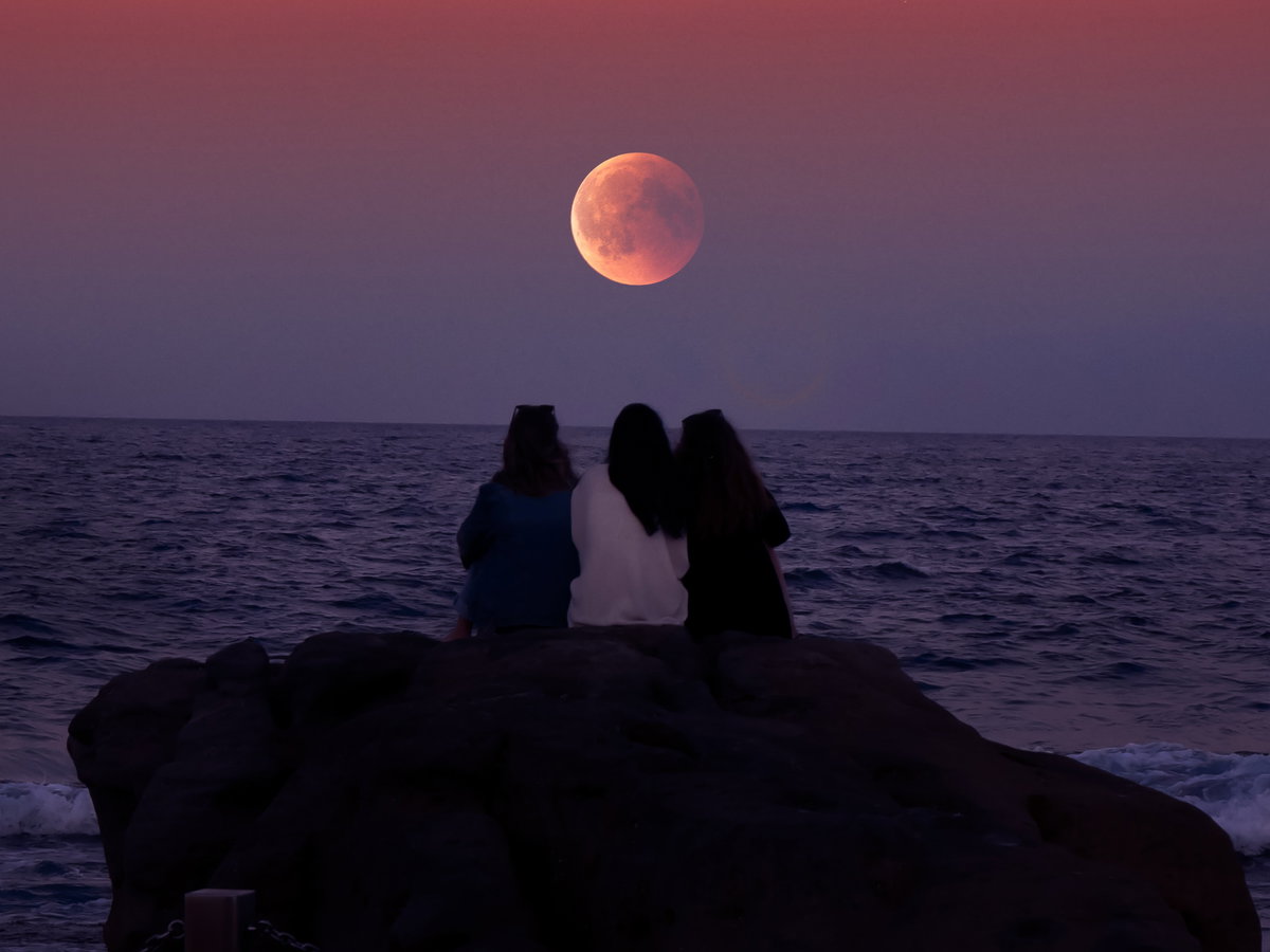 Drei Leute sitzen vor Supermond