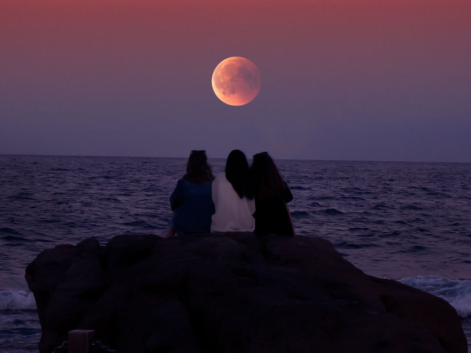 Drei Leute sitzen vor Supermond