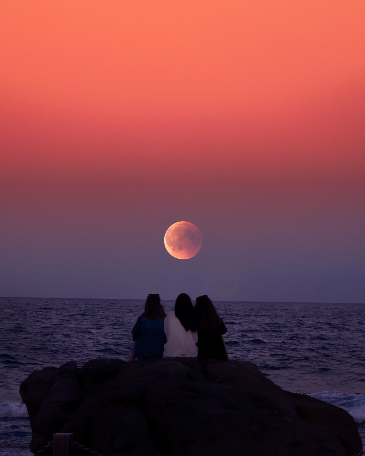 Drei Leute sitzen vor Supermond