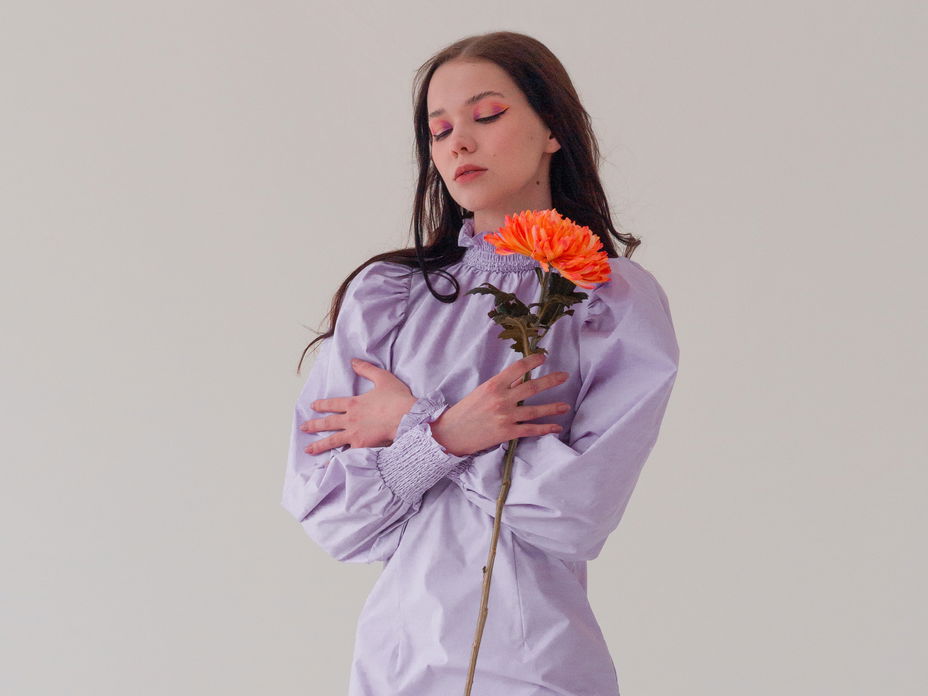 Horoskop Thema: Frau im lilafarbenen Kleid mit Blume