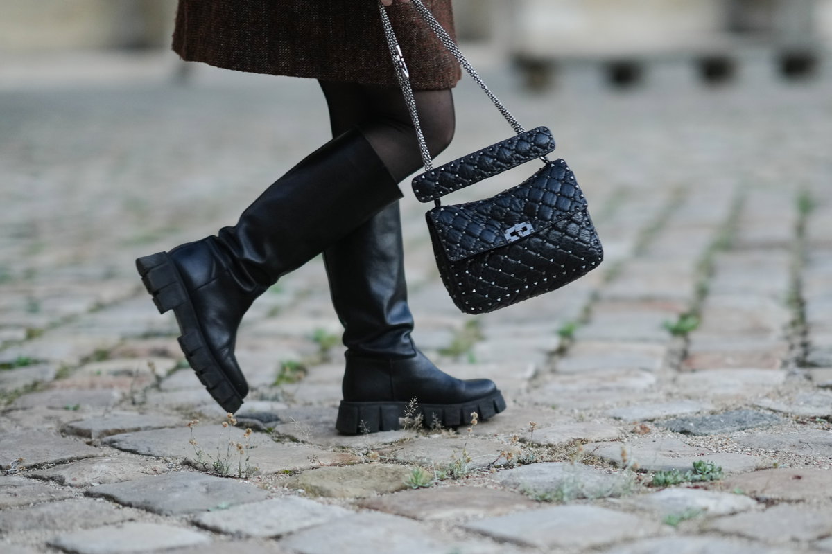 Frau trägt Stiefel mit Handtasche