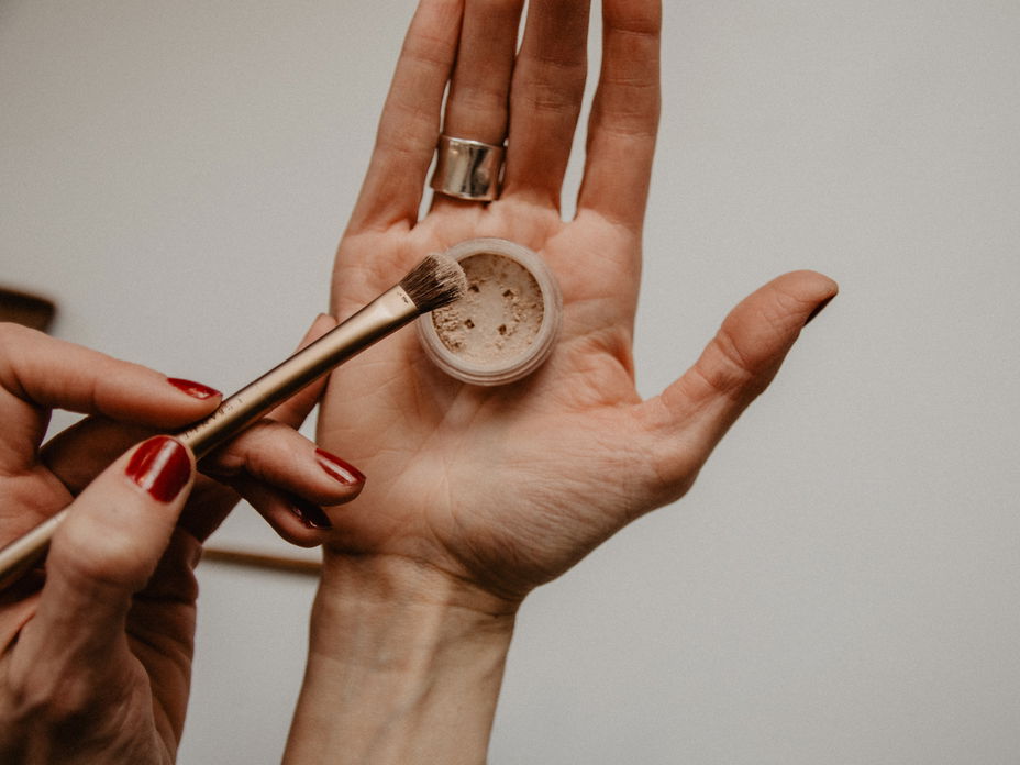 Hand hält Make up Puder und Pinsel