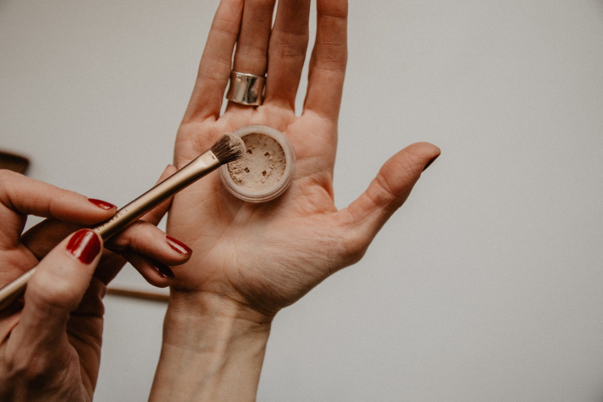Hand hält Make up Puder und Pinsel