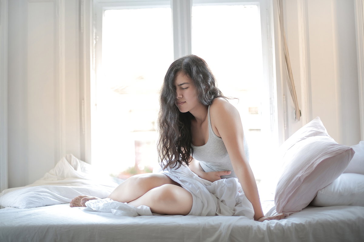 Frau mit Bauchschmerzen im Bett