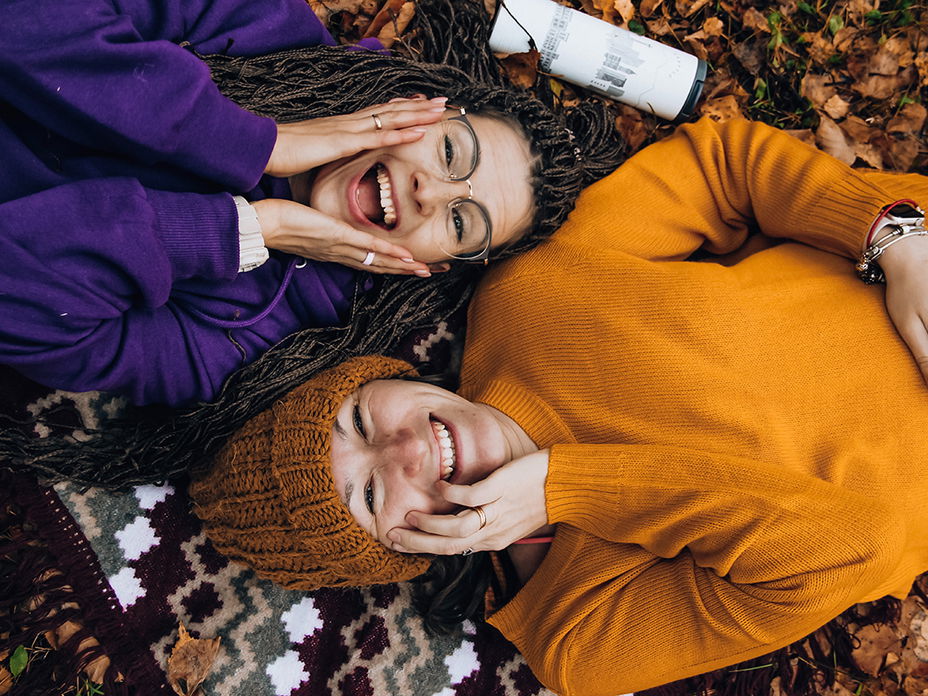 Zwei Frauen liegen nebeneinander und lachen