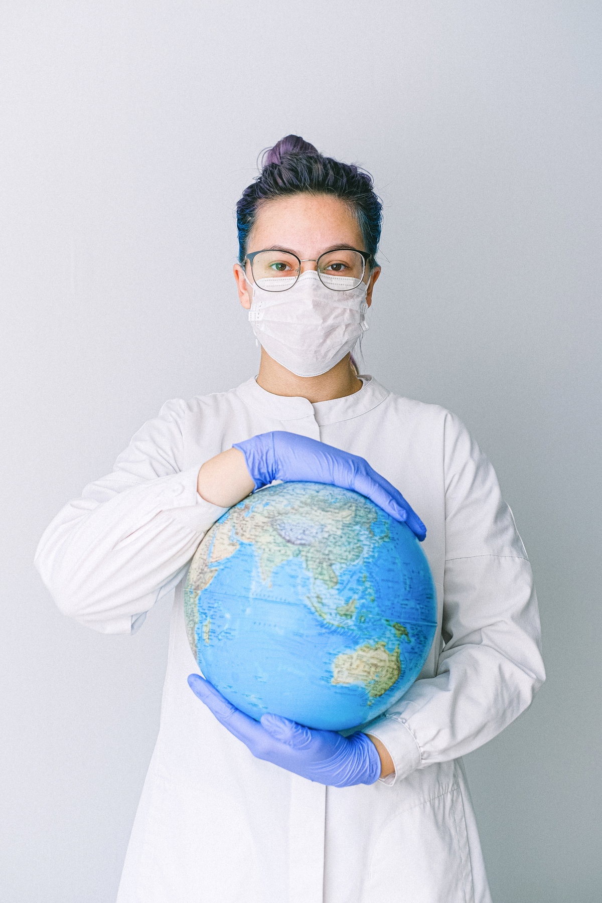 Frau mit Maske hat Globus in der Hand
