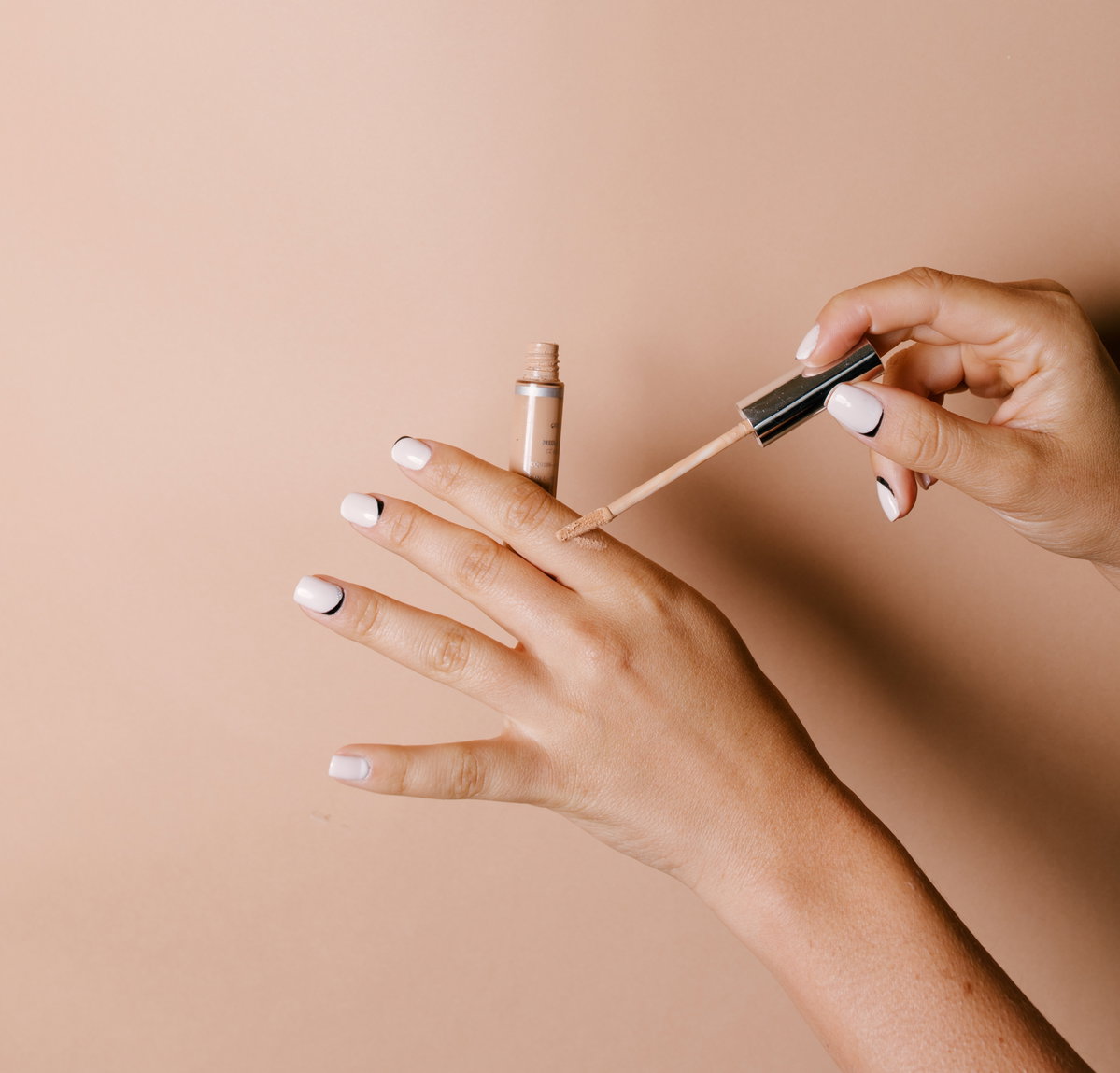 Concealer wird auf Hand aufgetragen