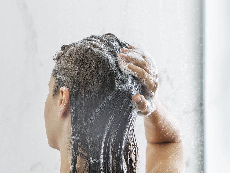 Frau wäscht sich die Haare mit Shampoo