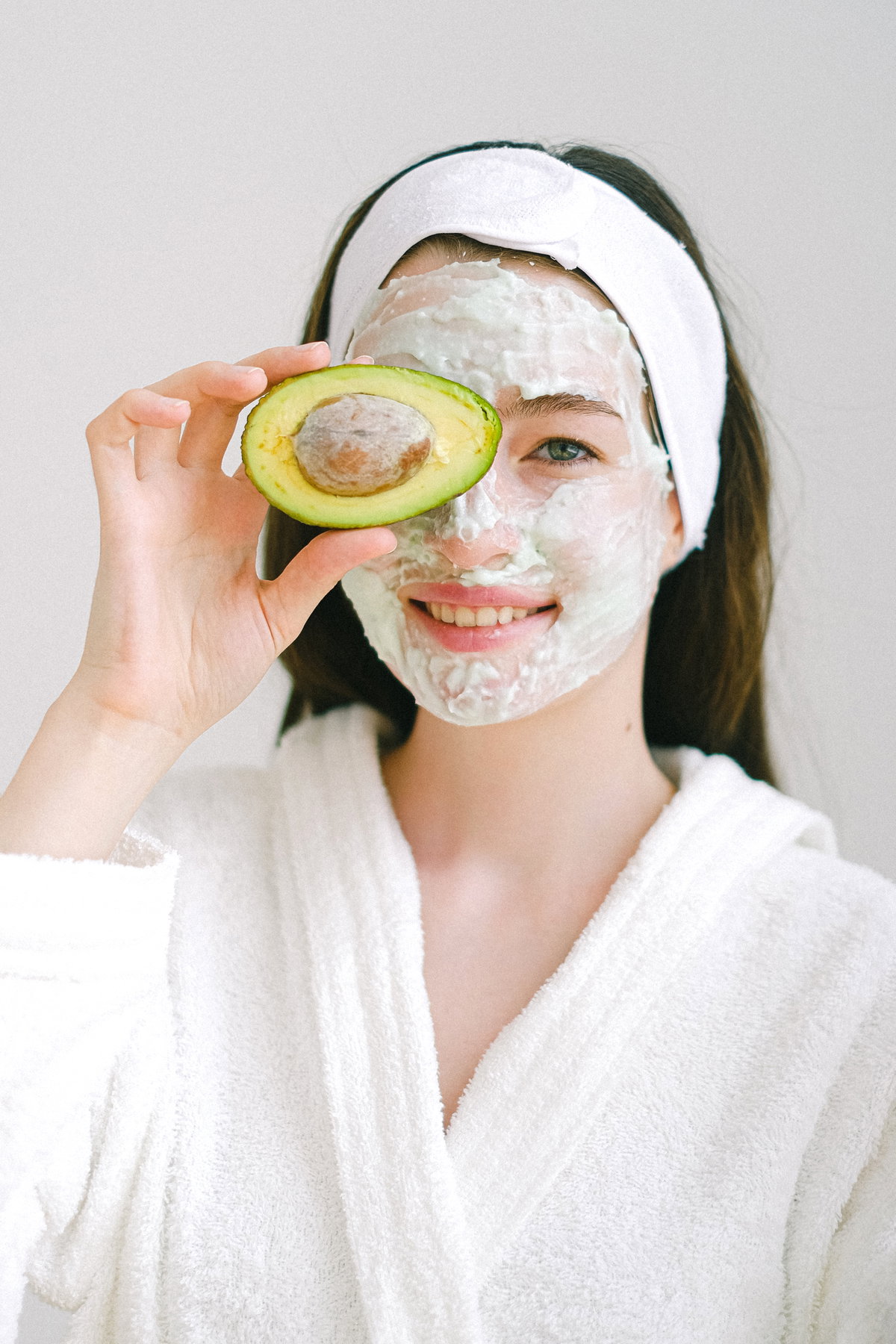 Frau mit Gesichtsmaske und Avocado