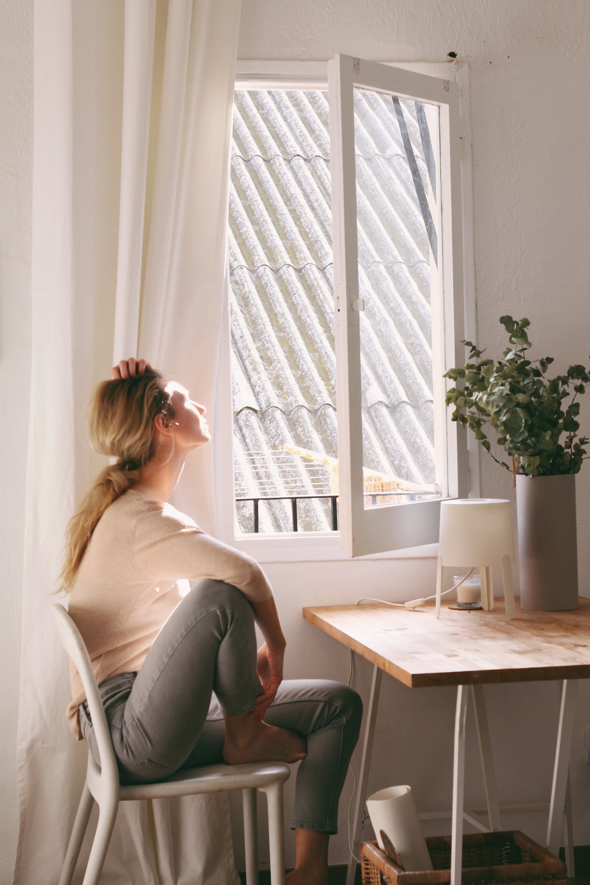 Frau schaut müde aus dem Fenster