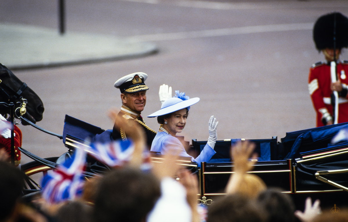 Queen Elizabeth und Prinz Phillip sitzen in einer Kutsche und winken