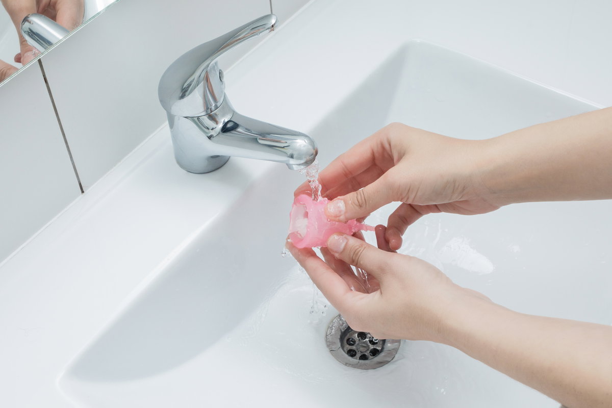 Menstruationstasse unter Wasserhahn reinigen