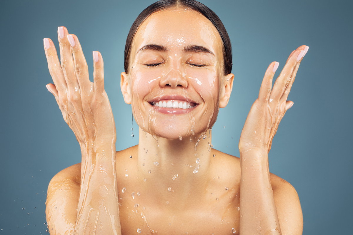 Frau wäscht sich mit Wasser das Gesicht