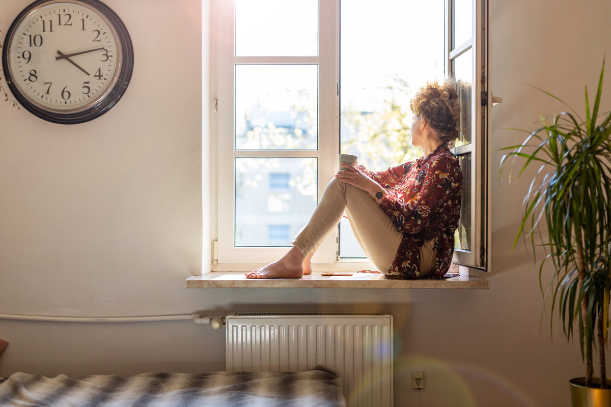 Frau sitzt alleine am Fenster